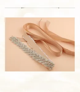 Détail macro de la ceinture de mariée ornée de strass étincelants sur ruban de satin champagne