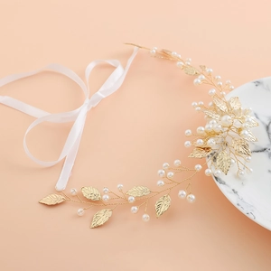 Vigne de cheveux de mariée avec feuilles dorées et perles sur fond rose pastel doux