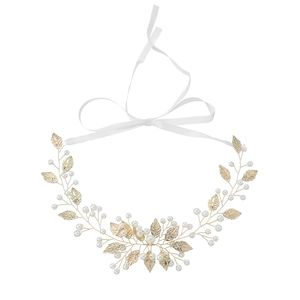Fascia da sposa fatta a mano con foglie dorate e perle bianche su uno sfondo bianco