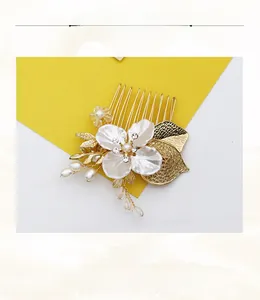 Détail du peigne à cheveux doré avec feuilles, perles et strass sur fond jaune et blanc