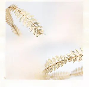 Detail of eco-friendly alloy golden leaves showing intricate texture and manual winding craft