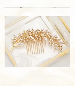 Detailed close-up of a vintage bridal hair comb with pearls and leaves on white silk