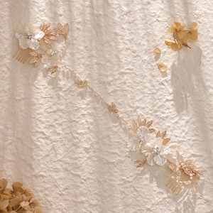 Eleganter goldener Brautschmuck mit weißen Seidenblumen und Perlen auf Texturpapier