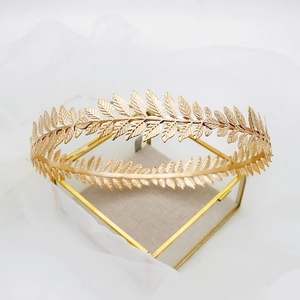 Elegant gold metal leaf crown bridal headpiece displayed on a white mesh background