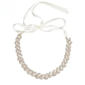 Detail of leaf-shaped rhinestone bridal headband with white silk ribbon in gold finish