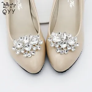 Close-up of sparkling rhinestone shoe clips on beige pointed-toe patent leather pumps