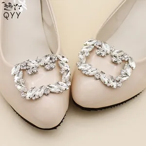 Close-up of sparkling heart-shaped rhinestone buckle on beige pointed flat shoes