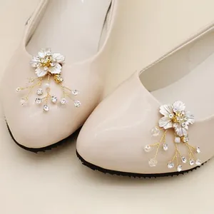 Detail of white flower shoe clips with crystals and pearls on cream patent leather shoes