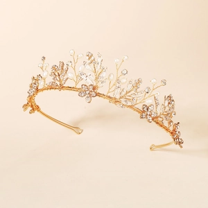 Close-up of handmade golden bridal headband with crystals, pearls and floral leaves
