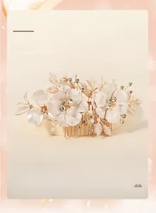 Macro detail of bridal hair comb with gold leaves, white petals and sparkling rhinestones