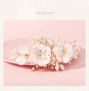 Detail of bridal hair comb featuring white flowers with pearls and crystals on gold wire