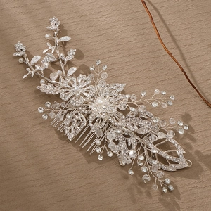 Silver bridal hair comb with vintage floral design, rhinestones and white pearls on brown background