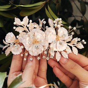 Floral bridal hair comb with white petals, pearls, and crystals on a golden alloy frame
