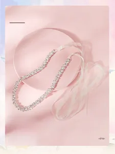 Détail de la ceinture de mariée en strass avec chaînes à griffes et rubans en satin blanc