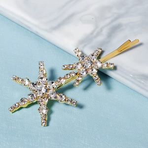 Elegant gold metal hair clip with sparkling star rhinestones on marble background