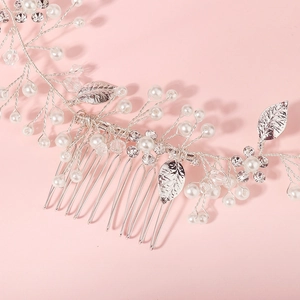 Silver bridal hair comb with pearls, crystals and leaf design on a pink background
