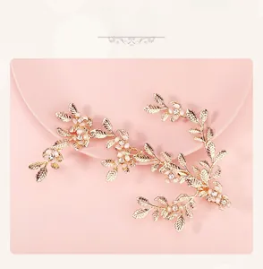 Golden leaf hair clip with white pearls and crystals displayed on a pink decorative tray
