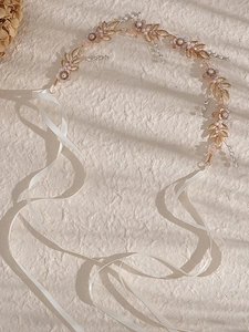 Dettaglio di tralcio per capelli da sposa con foglie dorate, perle e cristalli