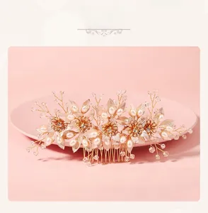Detail view of vintage golden floral hair comb with pearls and crystals on pink tray