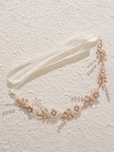 Dettaglio di un accessorio per capelli da sposa con fiori di cristallo e perle rosa su nastro