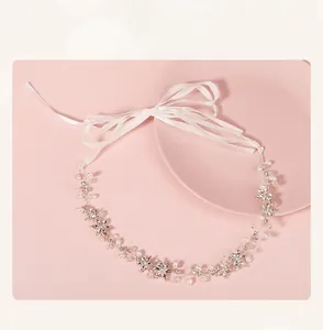 Close-up of handmade bridal headband with crystal flowers, pearls and white silk ribbons