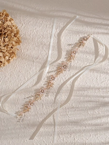 Dettaglio fascia da sposa con foglie dorate, perle e nappine di cristallo