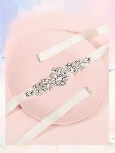 Dettaglio macro della cintura da sposa di lusso con fiori di cristallo e nastro di raso
