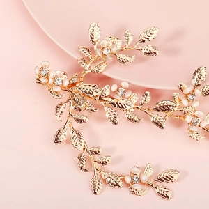 Elegant gold leaf hair clip with white pearls and sparkling rhinestones on pink background