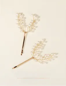 Detailed macro shot of handcrafted gold wire leaves and white pearls on bridal hair clips