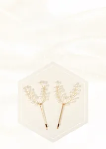 Detailed view of handmade leaf-shaped gold hairpins with elegant white pearls