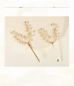 Detail of handcrafted gold hairpins with intricate pearl beadwork in a leaf design