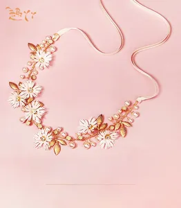Close-up of bridal headband with white silk flowers, golden metal leaves and faux pearls