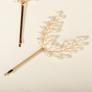 Elegant gold pearl leaf hair clip with handmade bead clusters on a minimalist background