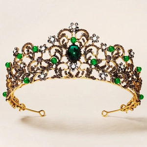 Detailed macro view of Baroque gold alloy crown featuring emerald green gems and rhinestones