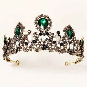 Macro detail of Baroque bridal crown with emerald green rhinestones and vintage gold finish