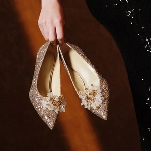 Close-up of luxury gold sequin bridal heels with crystal floral clip decoration