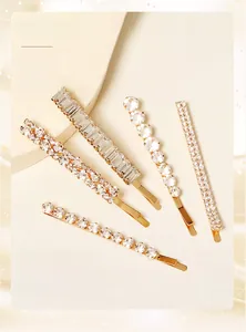 Détail de cinq barrettes dorées géométriques avec cristaux brillants pour coiffure mariée