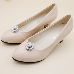 Detailed macro view of the sparkling rhinestone flower buckle on elegant cream bridal shoes