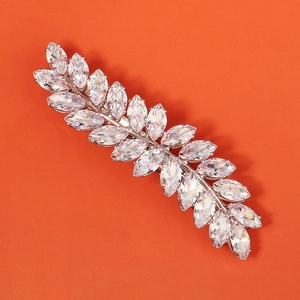 Close-up of wheat leaf hair clip with marquise-cut zircon on vibrant orange background