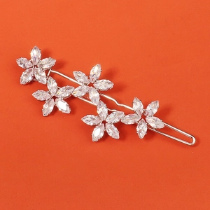 Détail d'une barrette argentée avec cinq fleurs en zircone sur fond orange vif