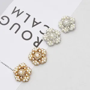 Close-up of handmade pearl and rhinestone flower bridal ear clips in gold and silver