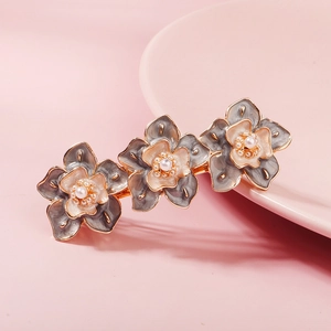 Gros plan détaillé d'une barrette à fleurs vintage avec émail gris et perles blanches