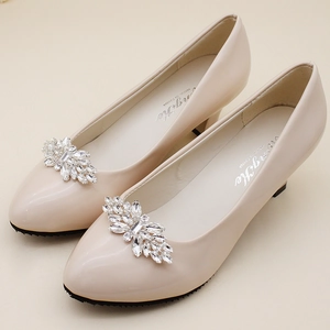 Detail of detachable rhinestone buckle on beige patent leather pointed toe block heels