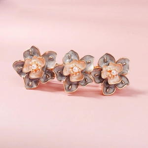 Détails de trois barrettes à fleurs avec des pétales en émail et des perles blanches