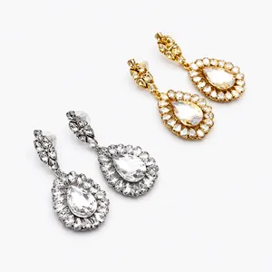 Macro shot of silver and gold teardrop bridal earrings with pear-cut halo crystals