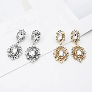 Detail view of silver and gold bridal earrings with intricate rhinestones and floral accents