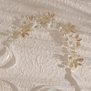 Handmade bridal daisy headband with white flowers, gold leaves and crystals on beige background