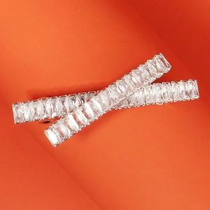 Close-up of two silver barrettes with pavé-set clear crystals on a bright orange background