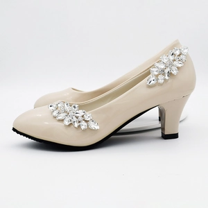 Detail of beige patent leather heels featuring elegant rhinestone floral accessories