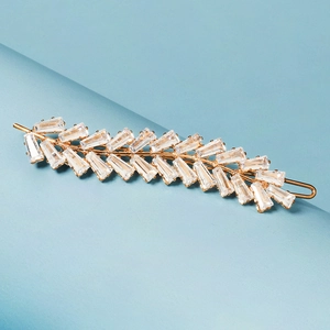 Détail d'une barrette dorée avec design de branche et cristaux scintillants